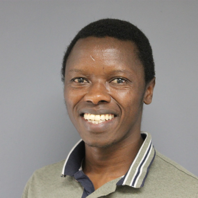 young black man with short hair, wearing a patterned shirt, smiling 